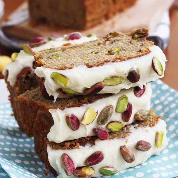 Pieces of banana and pistachio loaf stacked on a blue spotty cloth