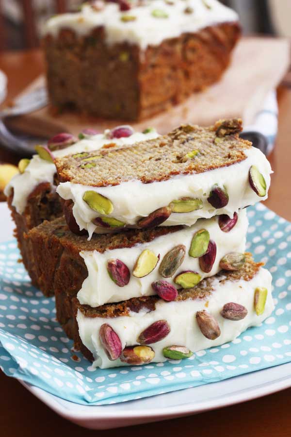 Pieces of banana and pistachio loaf stacked on a blue spotty cloth