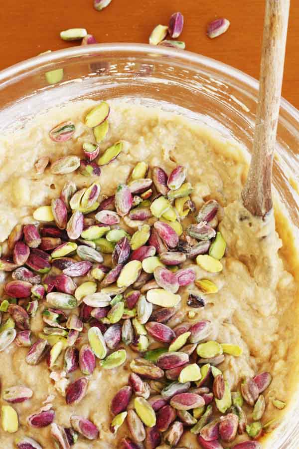 Closeup of a bowl of banana cake batter with pistachios sprinkled over the top