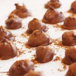 A close up of some chocolate orange truffles on a white background