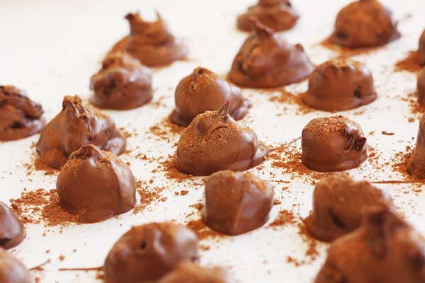 A close up of some chocolate orange truffles on a white background