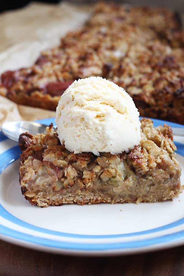 A Healthy Oat Slice With Rhubarb And Ginger on a blue and white plate with a fork and with ice cream on top