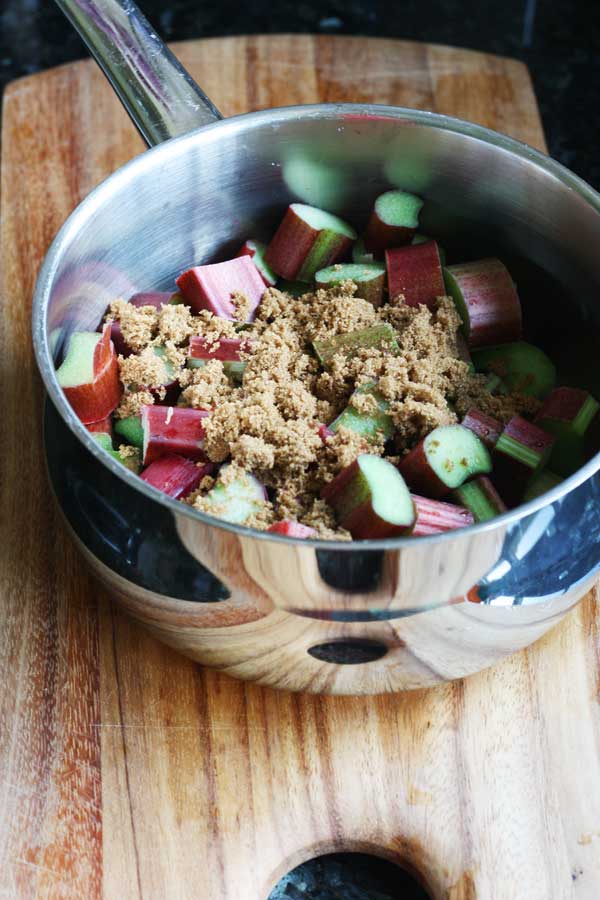 rhubarb and brown sugar in a saucepan on a wooden board