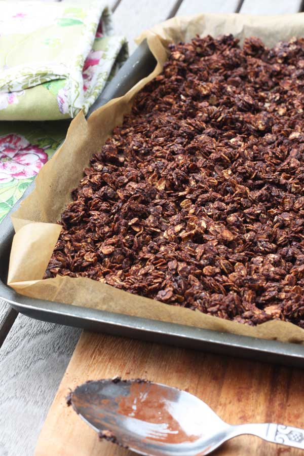 Chocolate granola on a baking tray just out of the oven with a tea towel in the background