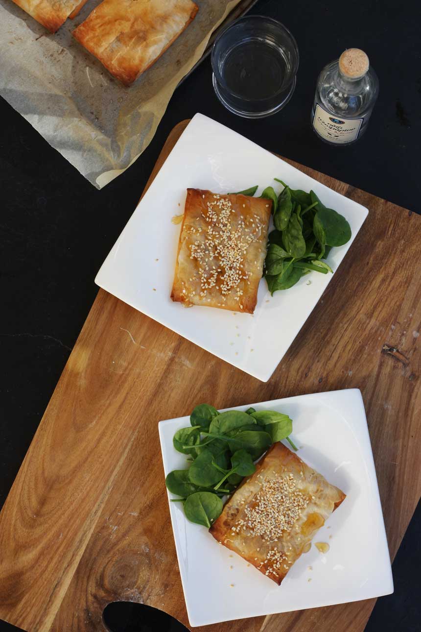 2 feta filo pies with honey on white square plates taken from above