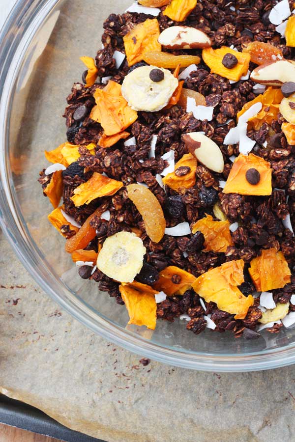 Closeup of part of a bowl of Tropical chocolate granola from above on a bench top.