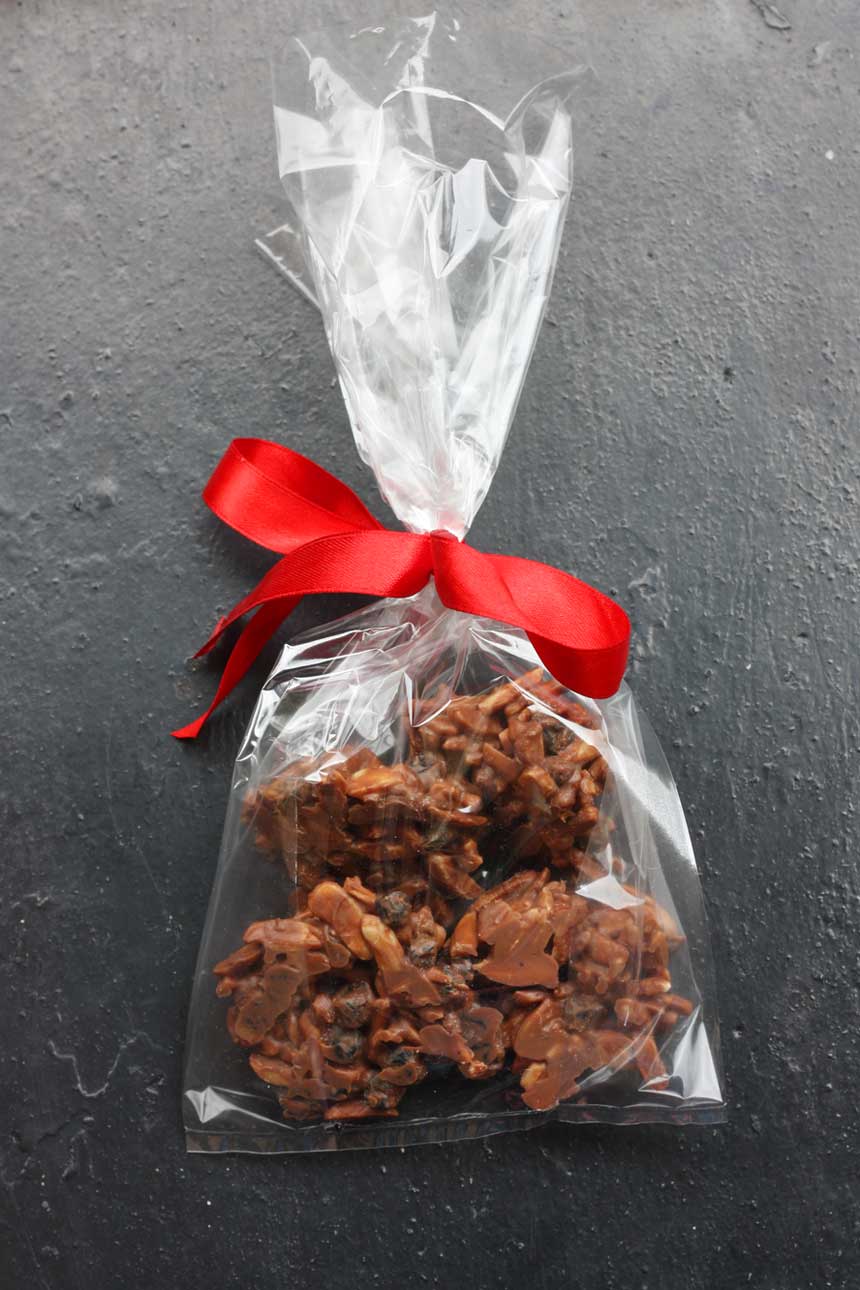 Finished chocolate rocks packaged to give as a gift with a red ribbon tied around the top and on a black background