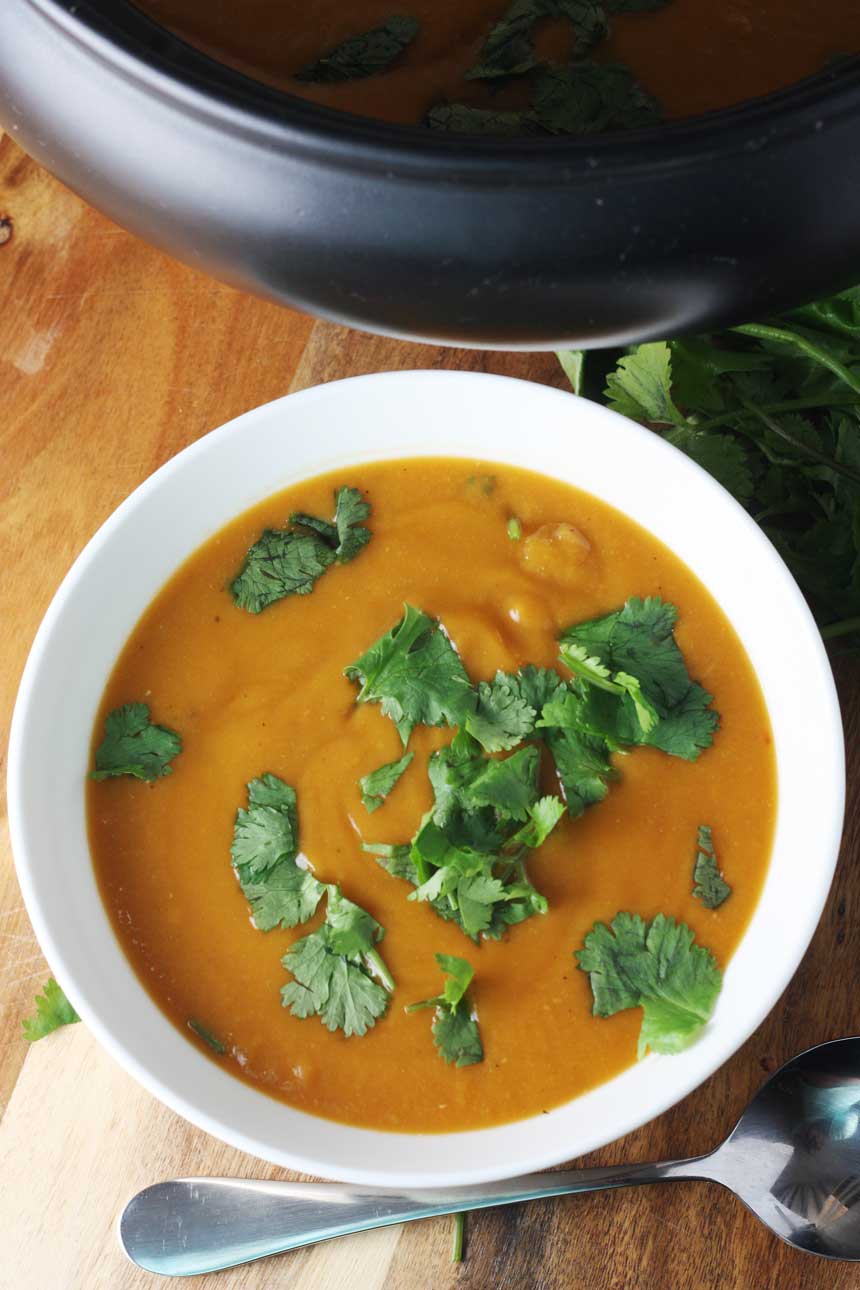 birds eye view of a bowl of Crock pot Thai pumpkin and red lentil soup on a wooden board