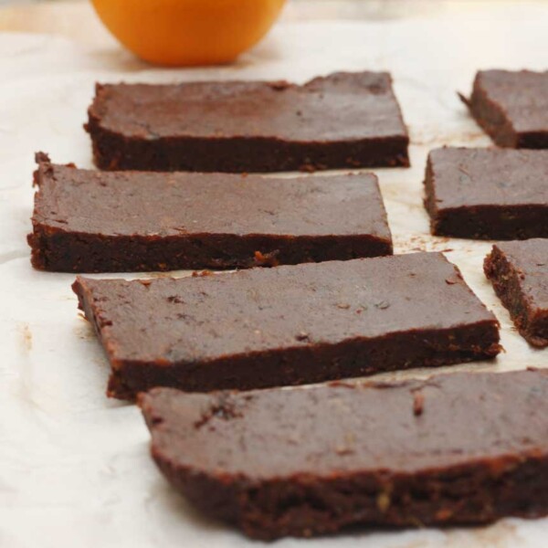 5-ingredient healthy chocolate orange date bars lined up on baking paper with orange in the background