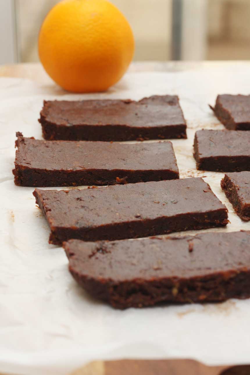 5-ingredient healthy chocolate orange date bars lined up on baking paper with orange in the background