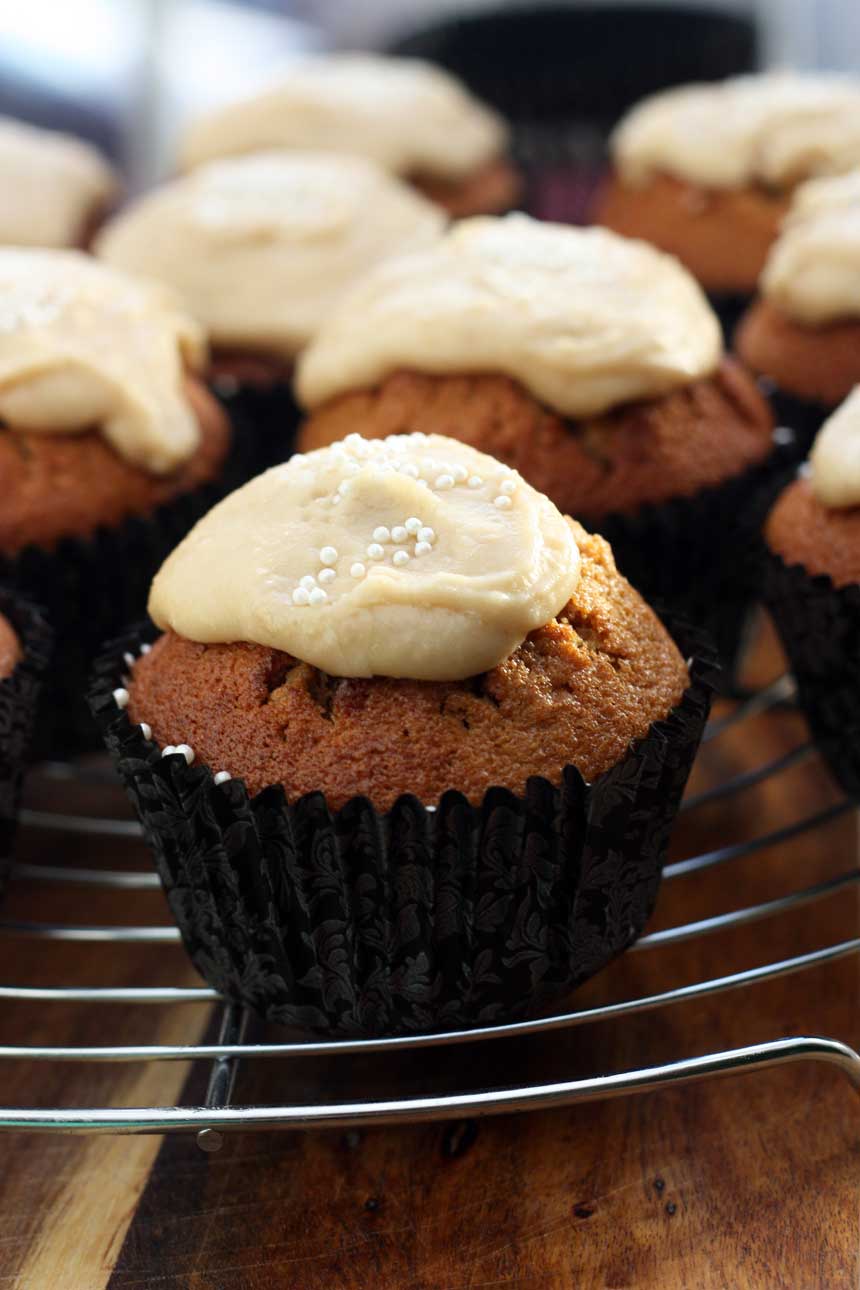 A close up of a gingerbread muffin with salted caramel frosting on a wire rack