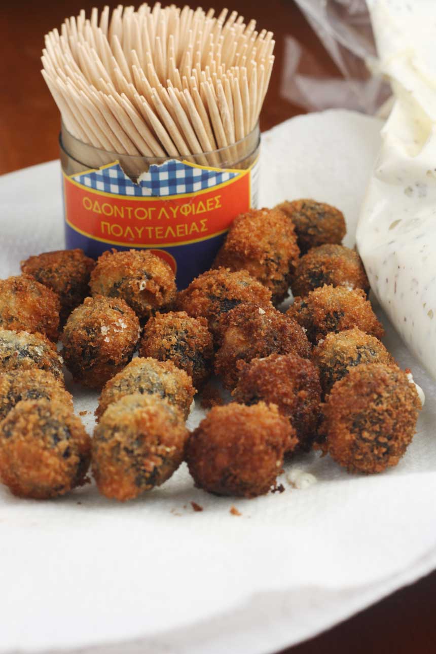 A plate of Greek fried olives with some cocktail sticks in the background