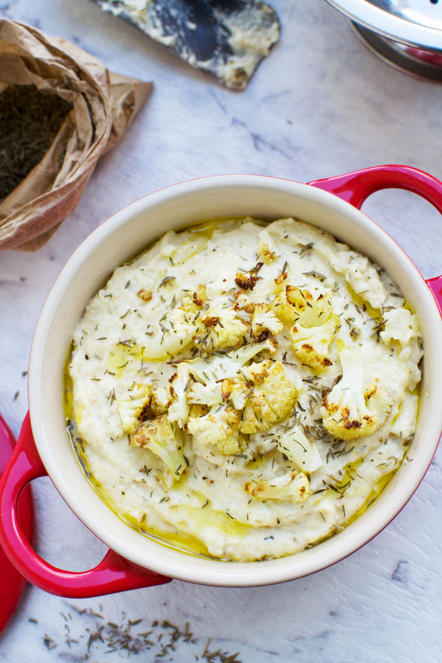 Cheesy roasted cauliflower and potato mash garnished with roasted cauliflower and olive oil in a red dish