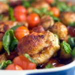 Closeup of a blue baking dish of chicken, chorizo and patatas bravas