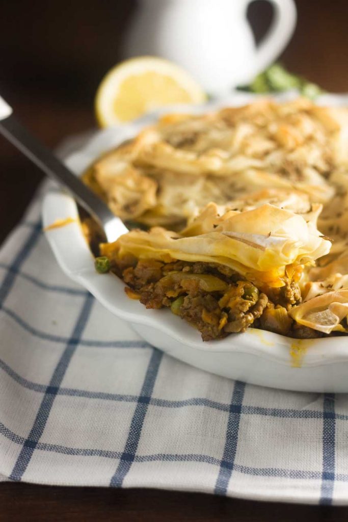 a samosa pie with a filo pastry top with a serving spoon in it