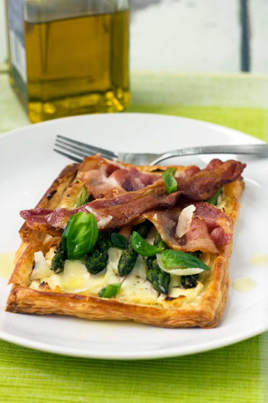 asparagus brunch tart with parmesan & basil on a white plate and on a green background