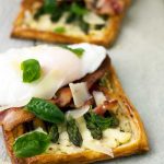 A close-up of an individual asparagus tartlet with bacon and an egg on top