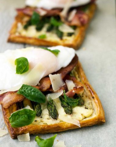 A close-up of an individual asparagus tartlet with bacon and an egg on top
