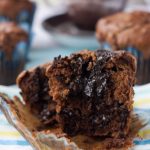 A soft-centered triple chocolate muffin split open so you can see the gooey instead - there are more muffins in the background