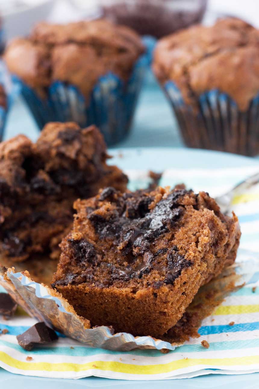 A soft-centred triple chocolate muffin sliced in half on a plate - there are more muffins in the background