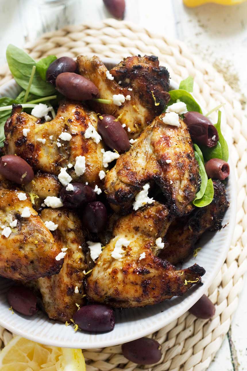 An overhead shot of Greek baked chicken wings with feta and olives on top