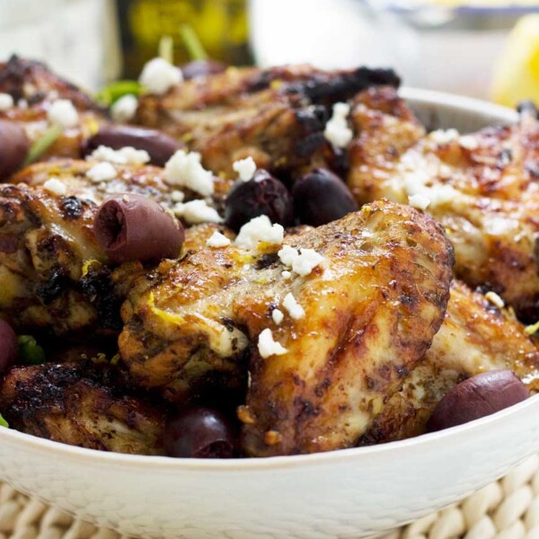 A big bowl of Greek baked chicken wings with olives and feta sprinkled on top