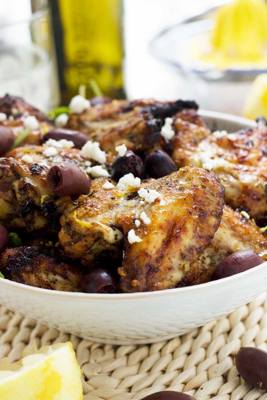 A big bowl of Greek baked chicken wings with olives and feta sprinkled on top