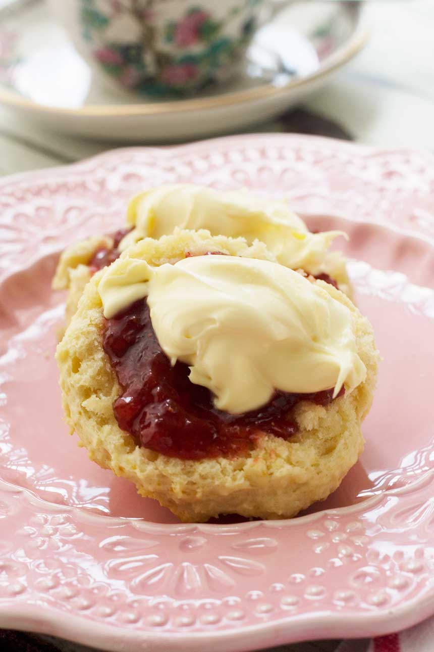A close up of 3-ingredient scones with jam and cream on a pink plate.