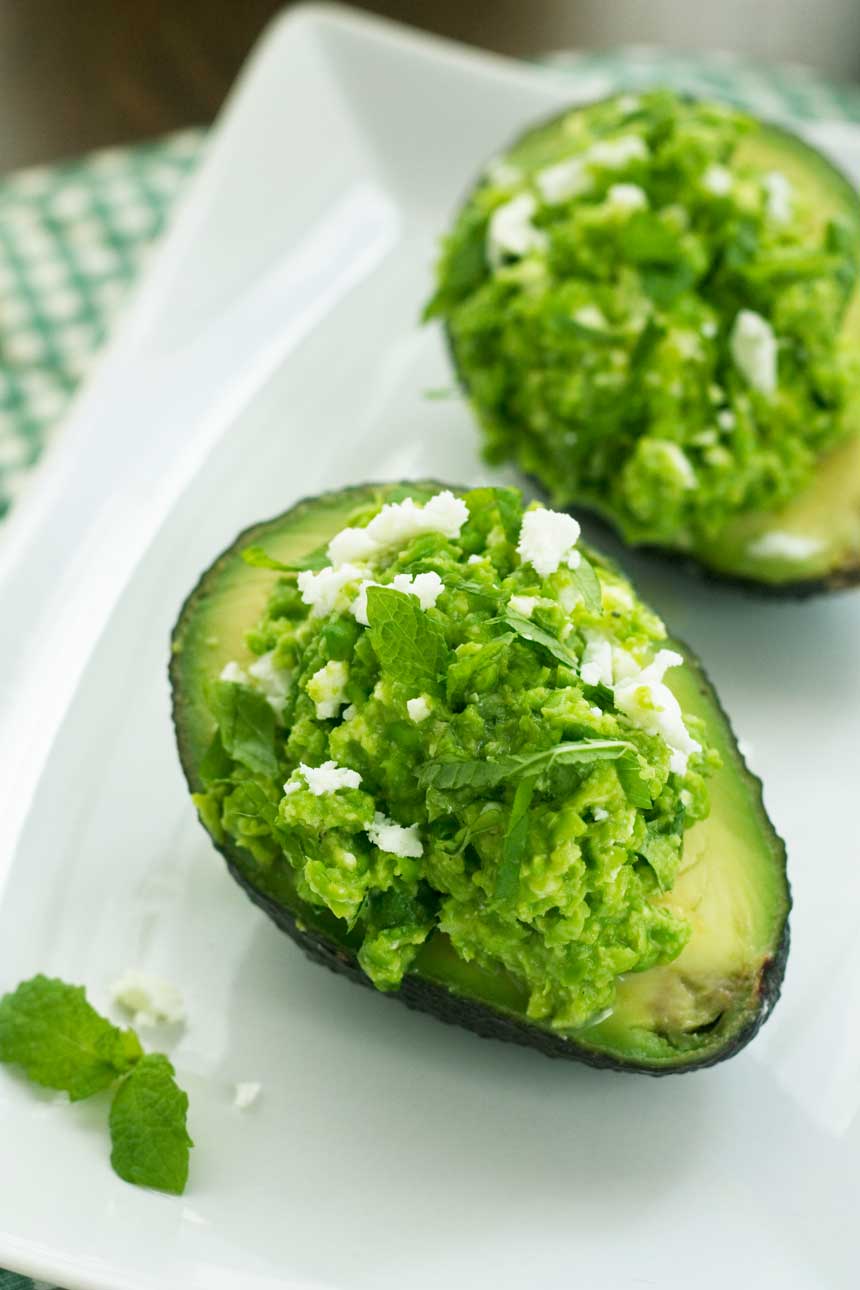 Overhead view of Pea, mint and feta avocado boats on a white plate.