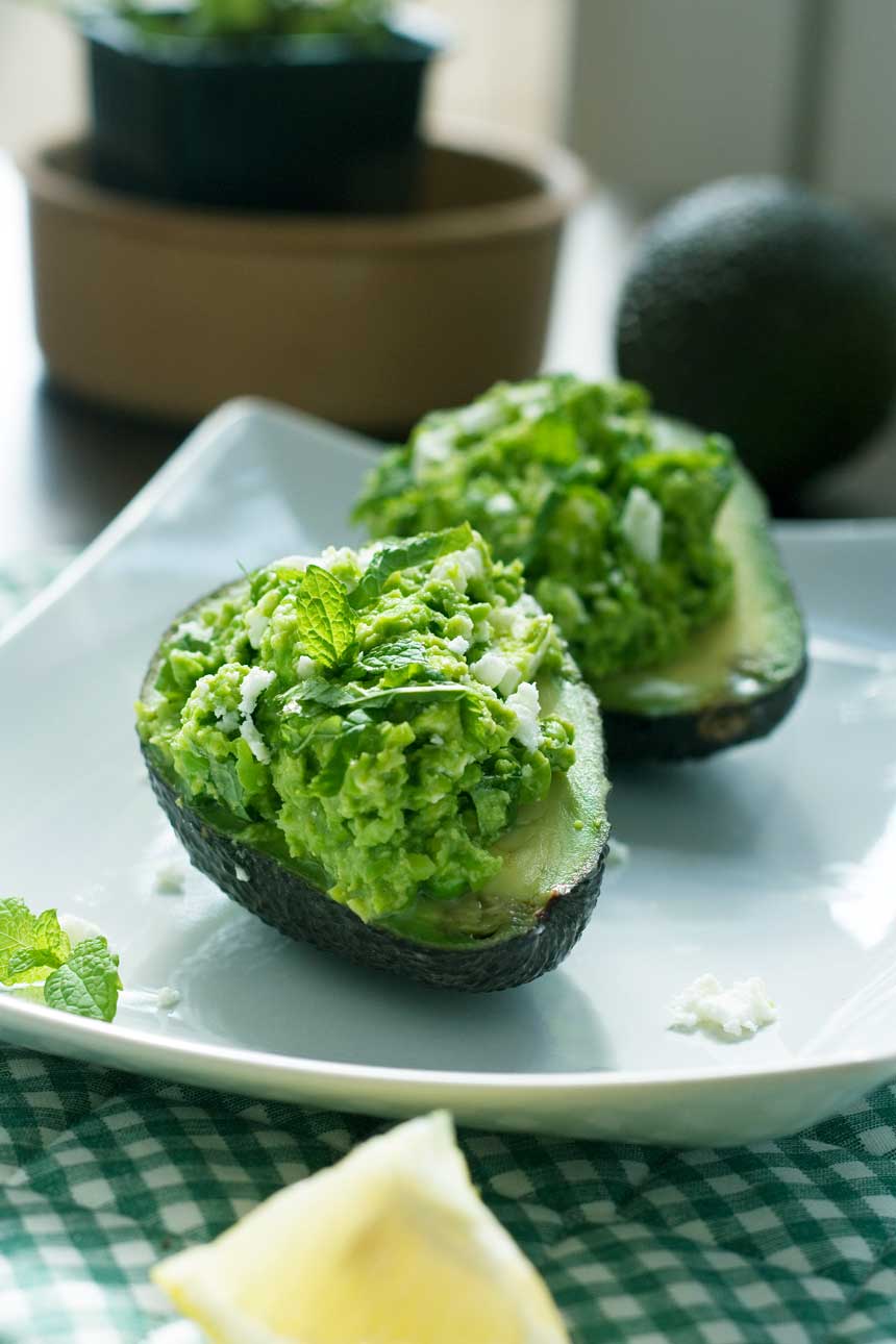 Pea, mint and feta avocado boats on a white square plate.