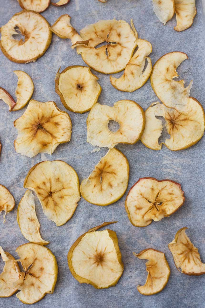 A close up dried apples on baking paper from above.