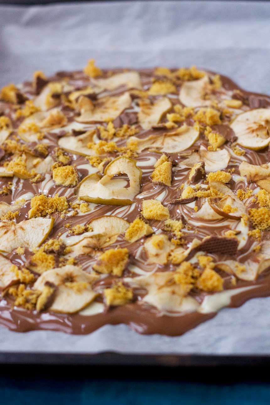 A closeup of toffee apple chocolate bark on baking paper before being cut up into pieces.