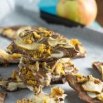 A stack of toffee apple chocolate bark on baking paper with an apple in the background