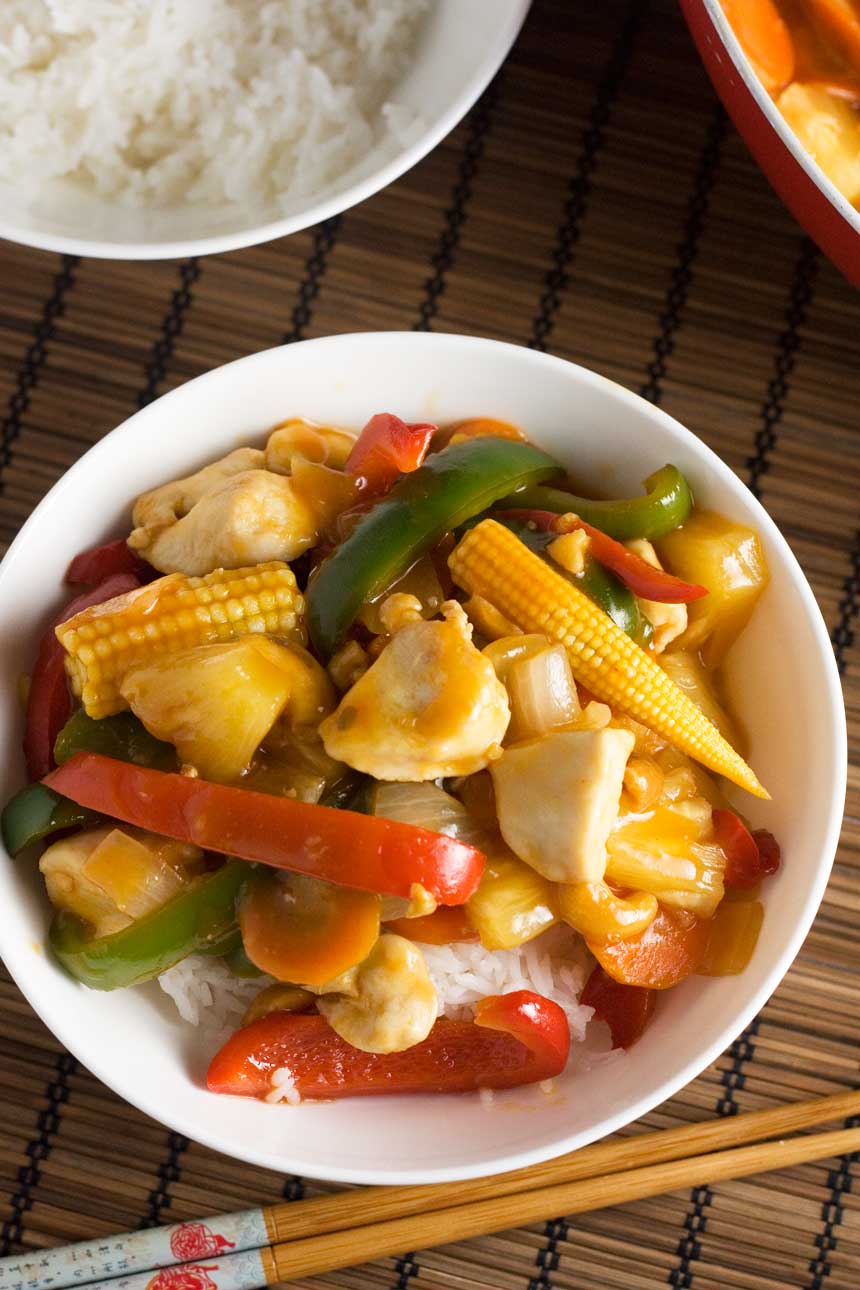 An overhead shot of a dish of quick sweet and sour chicken on a brown place mat