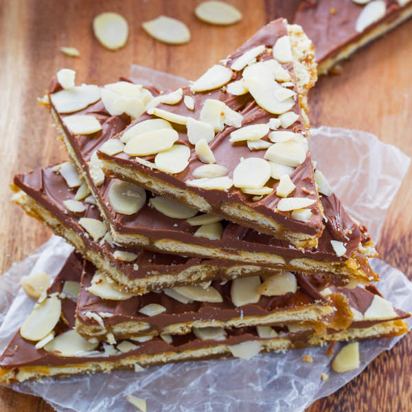 Almond rum saltine toffee piled up on baking paper and a wooden table.