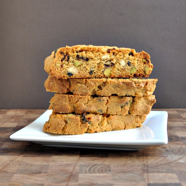 A small stack of Cranberry white chocolate biscotti on a square white plate and wooden table.