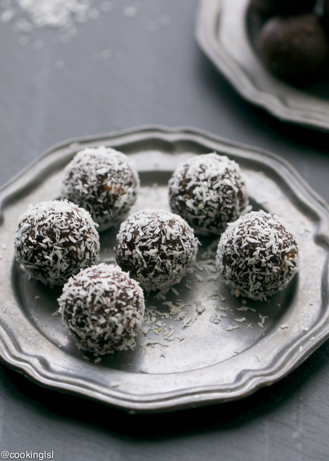 A close up of chocolate truffles on a decorative plate and a dark background.