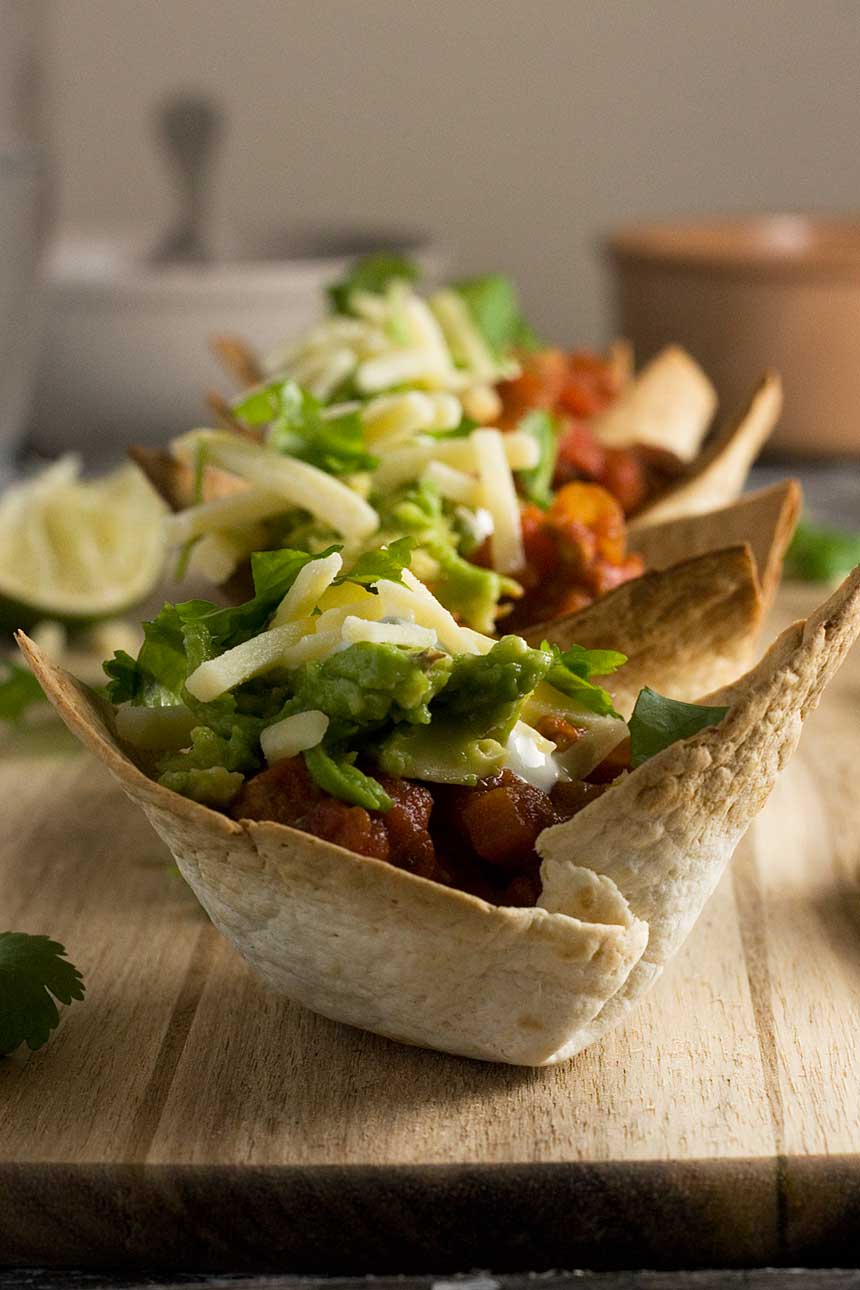 A turkey chili mini taco bowl closeup on a wooden board.