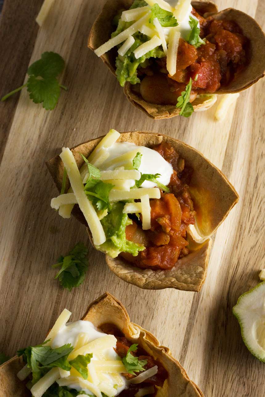 turkey chili mini taco bowls from above on a wooden board.