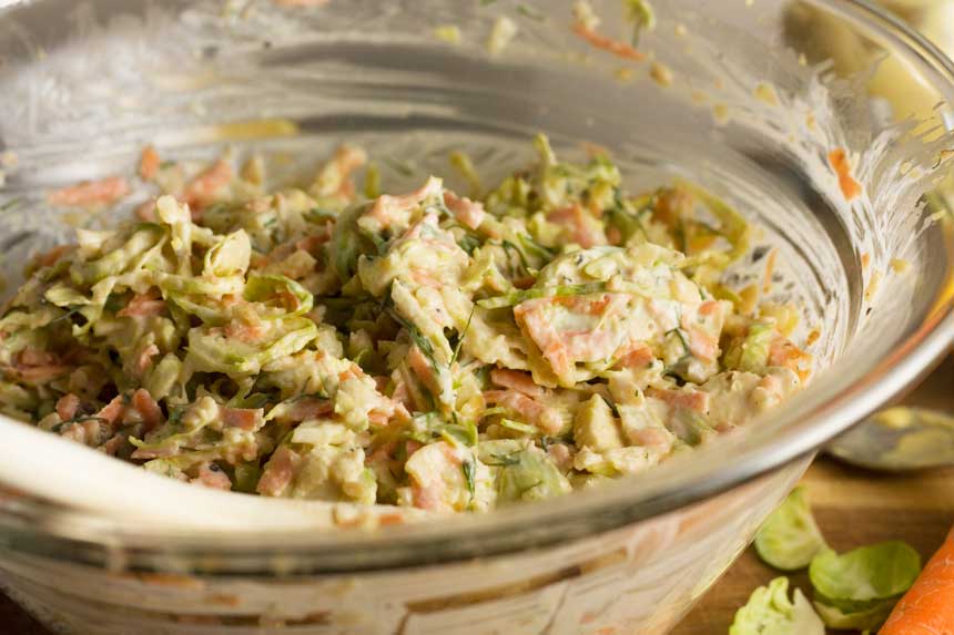 Closeup of a clear bowl of brussels sprouts coleslaw.