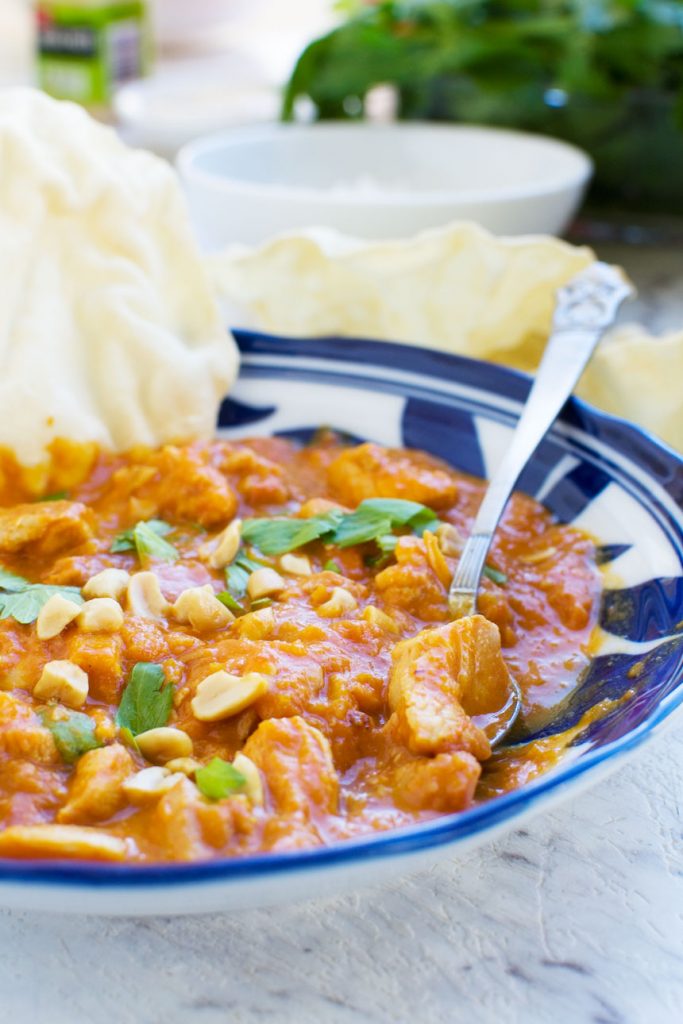 A Thai chicken and butternut squash curry with peanuts, coriander & poppadoms, with a spoon in it