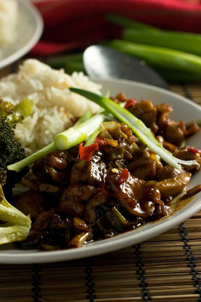 A closeup of a plate of 15-minute Shanghai chicken with rice and ingredients in the background