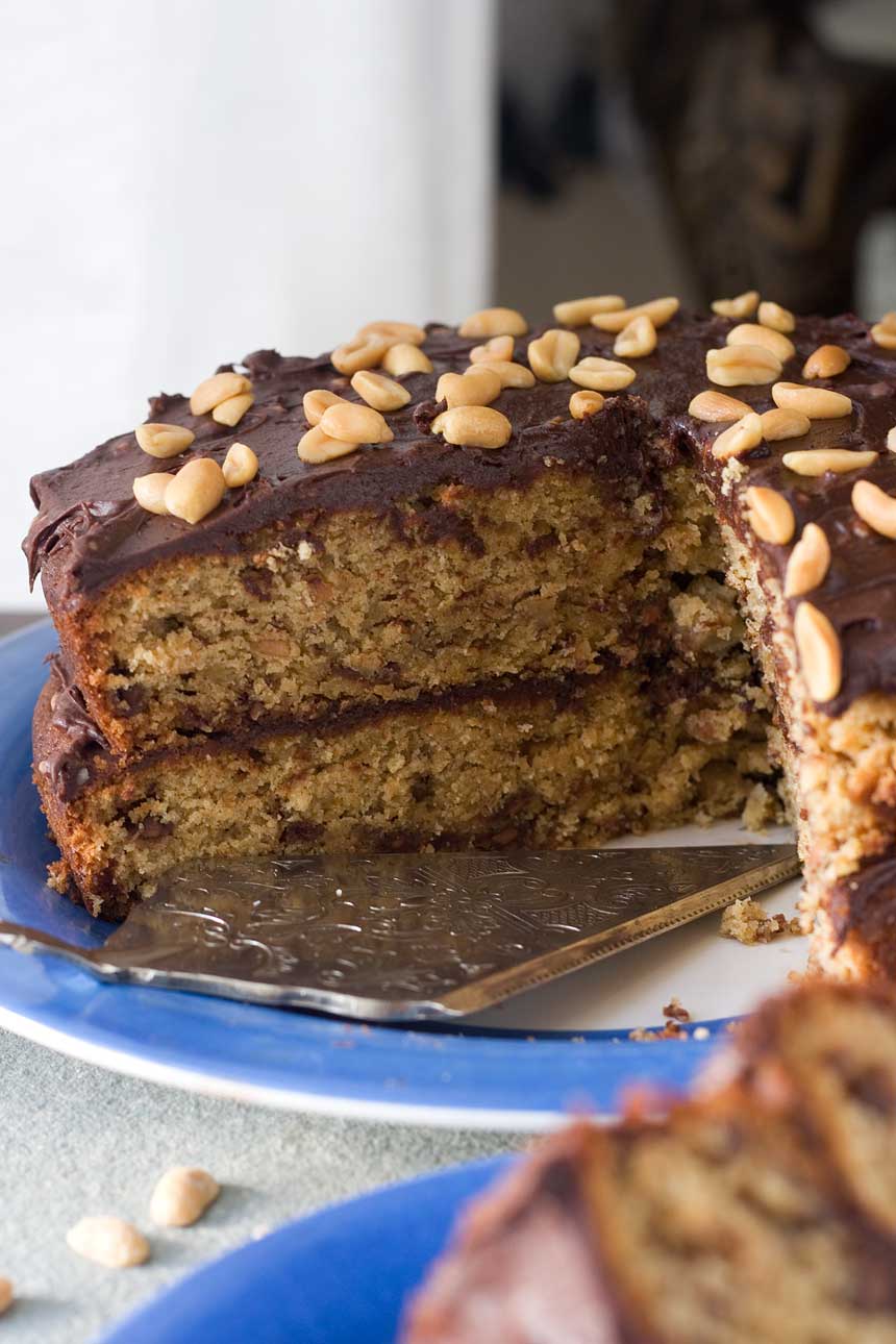 The inside of a Peanut Butter, banana and choc chip cake with pieces cut out of it on a blue plate and with a decorative cake slice.