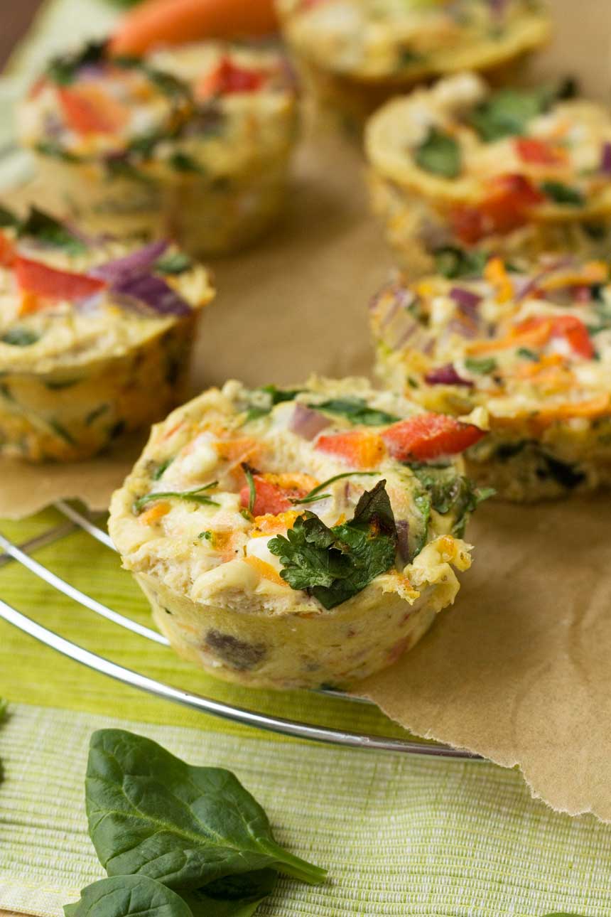 Veggie muffin fritattas on brown paper and a wire rack and a green cloth.