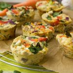 A closeup of veggie muffin frittatas on brown paper and a wire rack and on a green cloth.