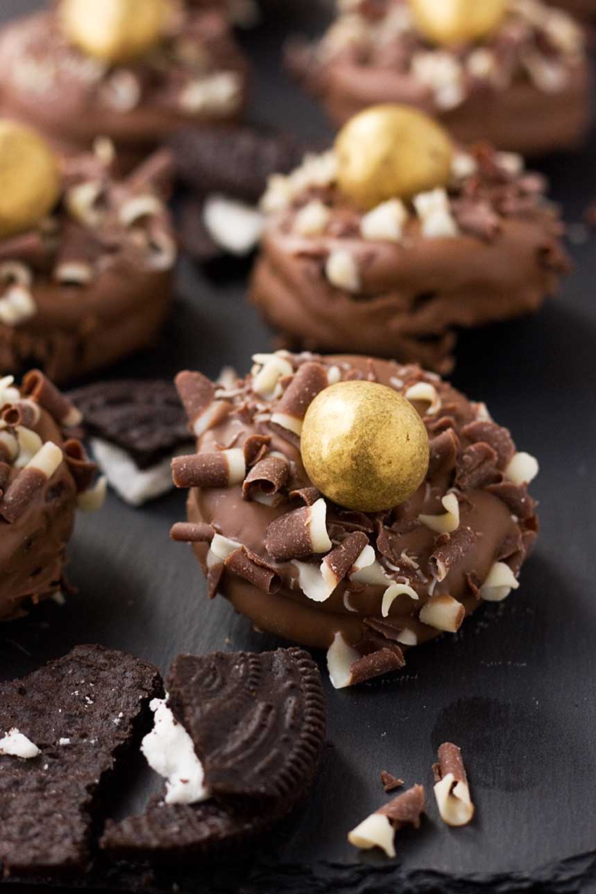 A close up of a chocolate dipped Oreo with a golden egg on top with others around it