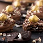 A close up of chocolate dipped oreos on a black slate board