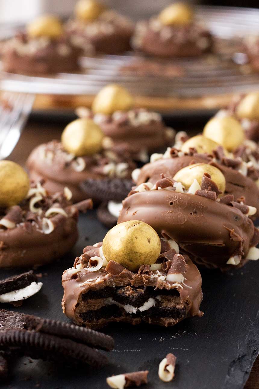 A close up of a chocolate dipped oreos with gold chocolate eggs on top