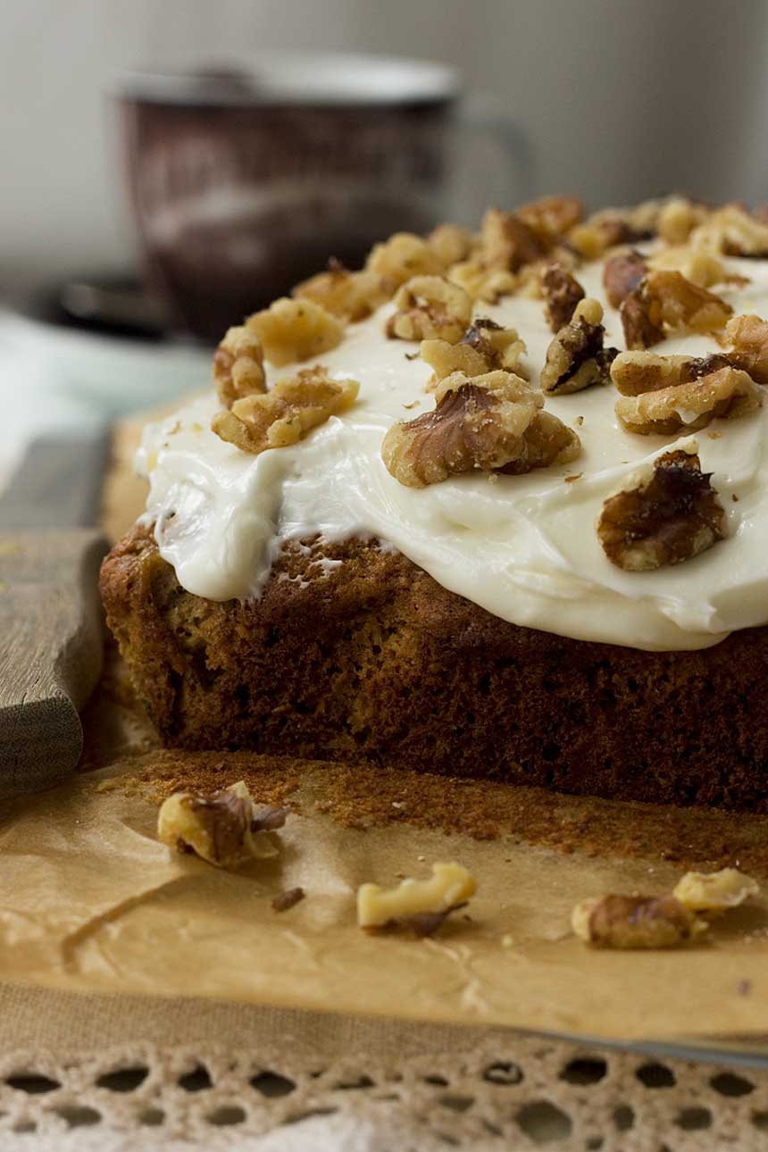 A whole pineapple, coconut and banana cake with cream cheese icing and walnuts on top