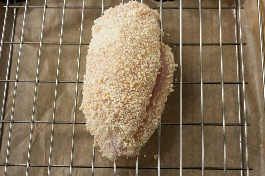 Crispy baked ham and cheese stuffed chicken on a grill from above before cooking.